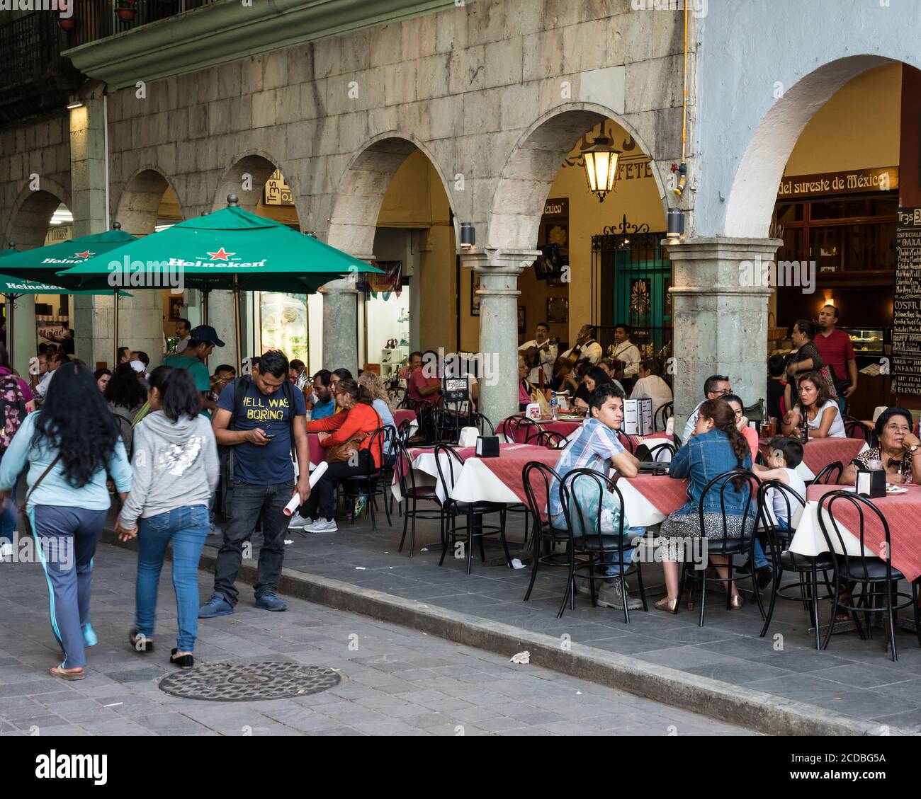 Tourists dining in restaurants in the old historic buildings surrounding the Zocalo, or main plaza in the historic center of Oaxaca, Mexico. Stock Photo