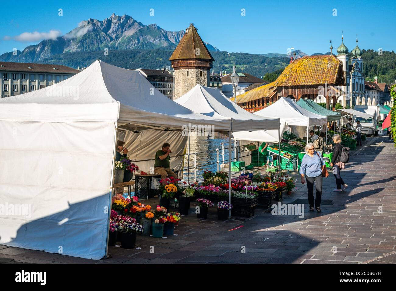 Lucerne Switzerland , 30 June 2020 : Lucerne morning farmer market with people and stalls with Chapel bridge landmark and Pilatus mount in background Stock Photo