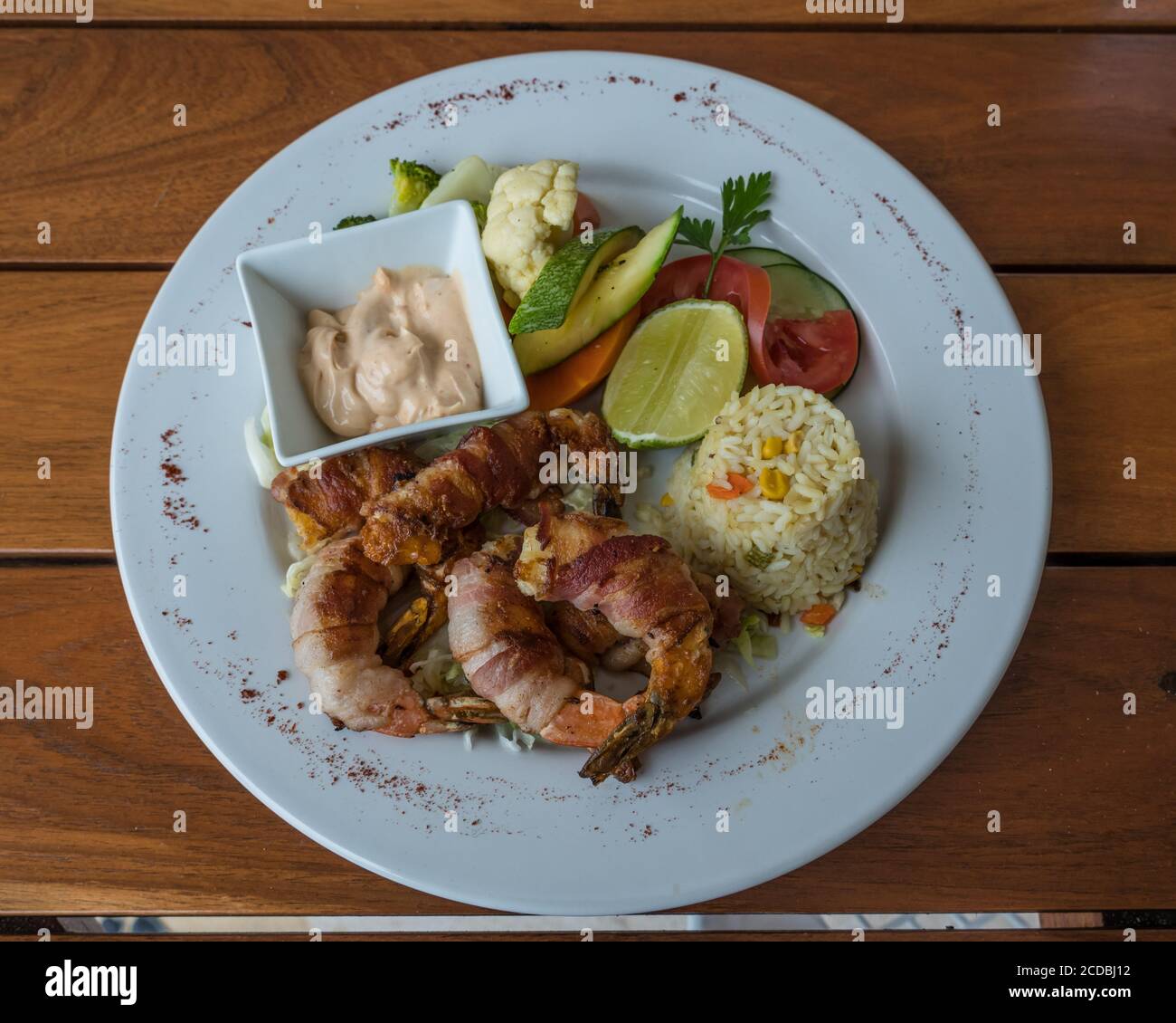 Bacon-wrapped shrimp with a lime, rice and vegetables by the Caribbean in Mexico. Stock Photo