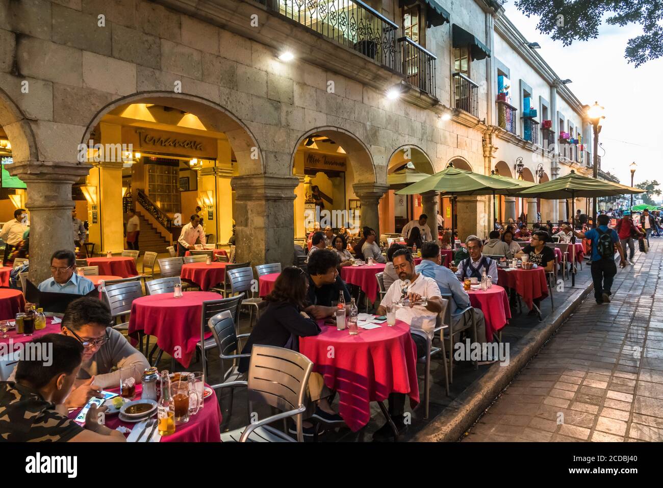 Tourists dining in restaurants in the old historic buildings surrounding the Zocalo, or main plaza in the historic center of Oaxaca, Mexico. Stock Photo