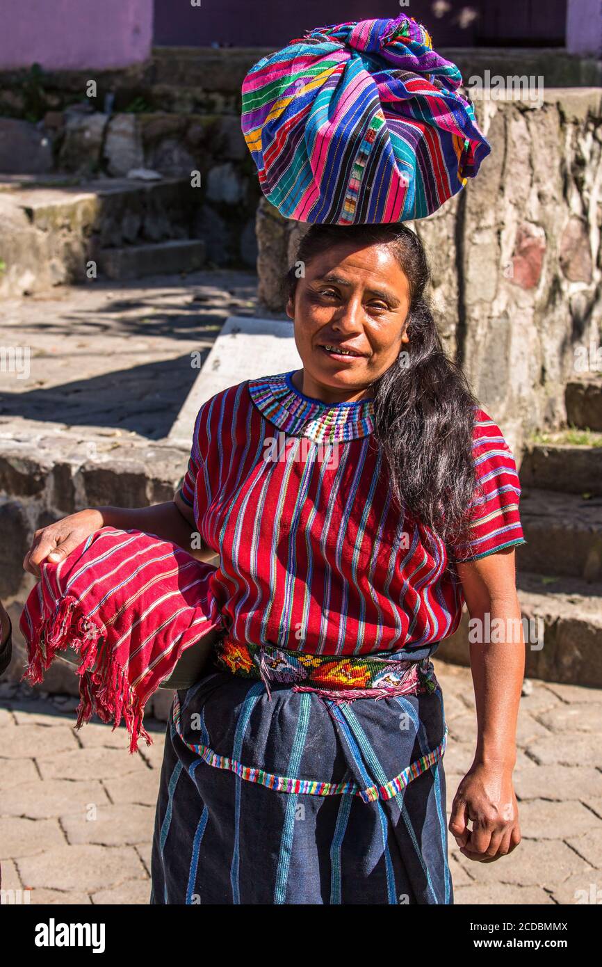 A Cakchiquel Mayan woman in traditional dress carries her wares to