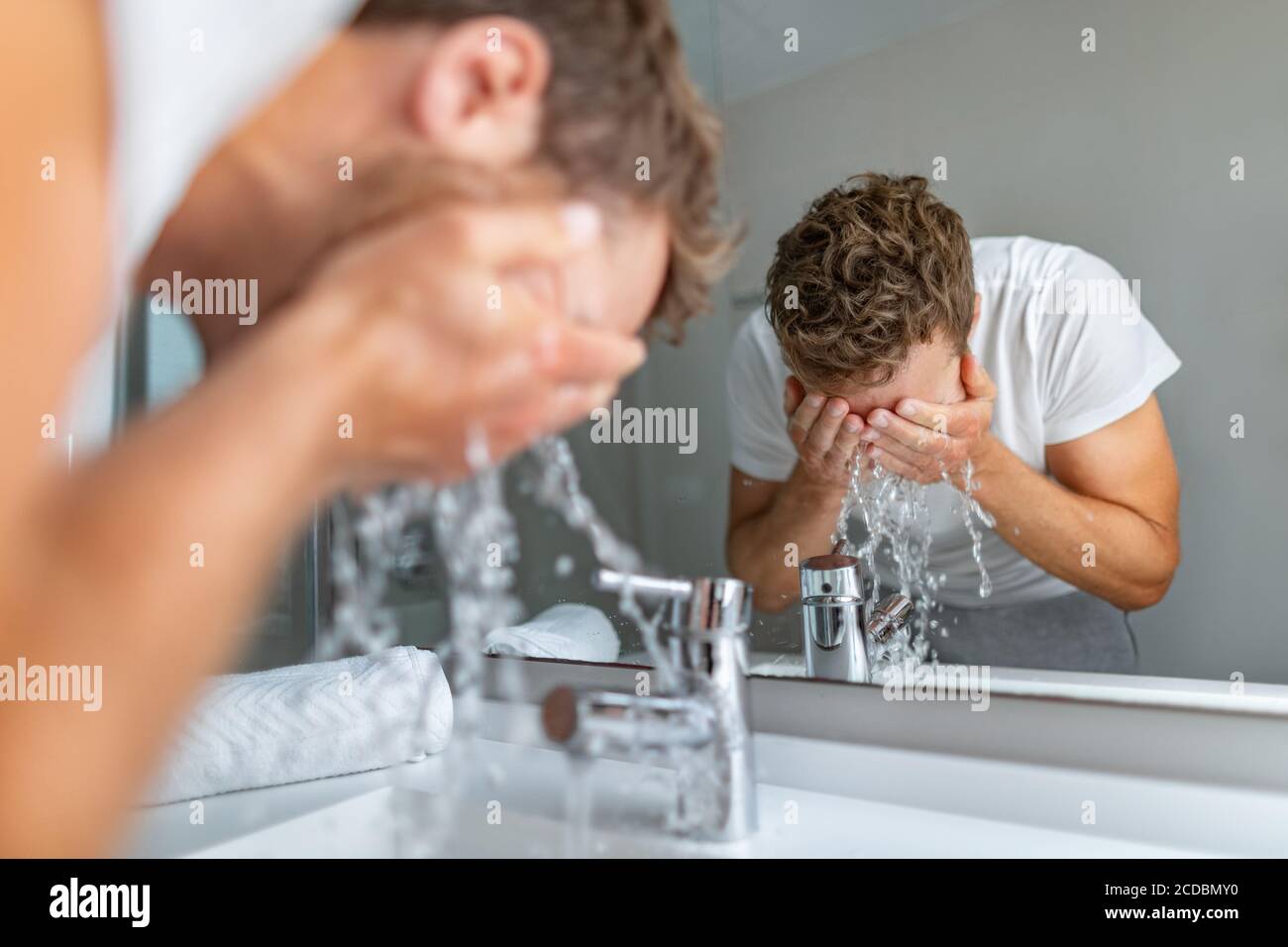 Face wash man splashing water cleaning washing face with facial soap in bathroom sink. Men taking care of skin, morning face wash routine for cleaning Stock Photo
