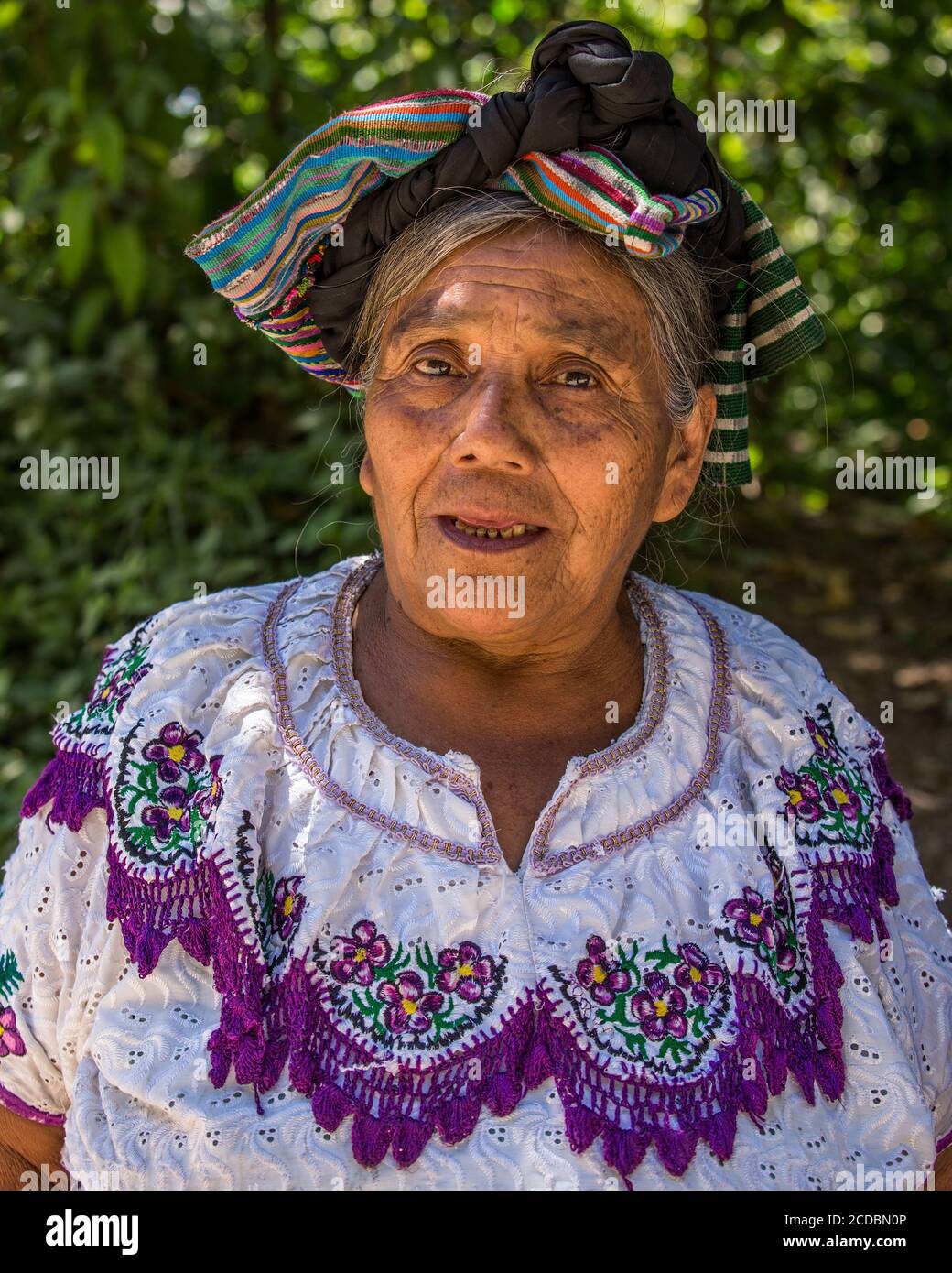 An older Tzutujil Mayan woman in traditional dress poses for a picture ...