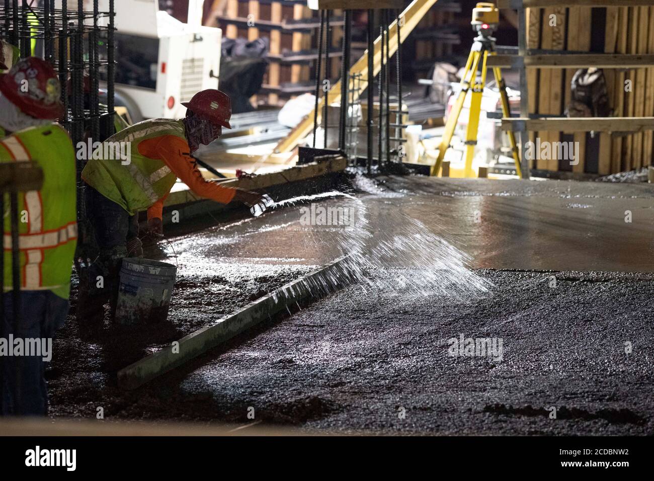 Austin, TX USA August 22, 2020: Experienced concrete crews conduct a night pour and early morning smoothing and shaping on the top floors of a high-rise parking garage in downtown Austin. Major construction projects continue unabated during the coronavirus shutdowns in Texas. Stock Photo