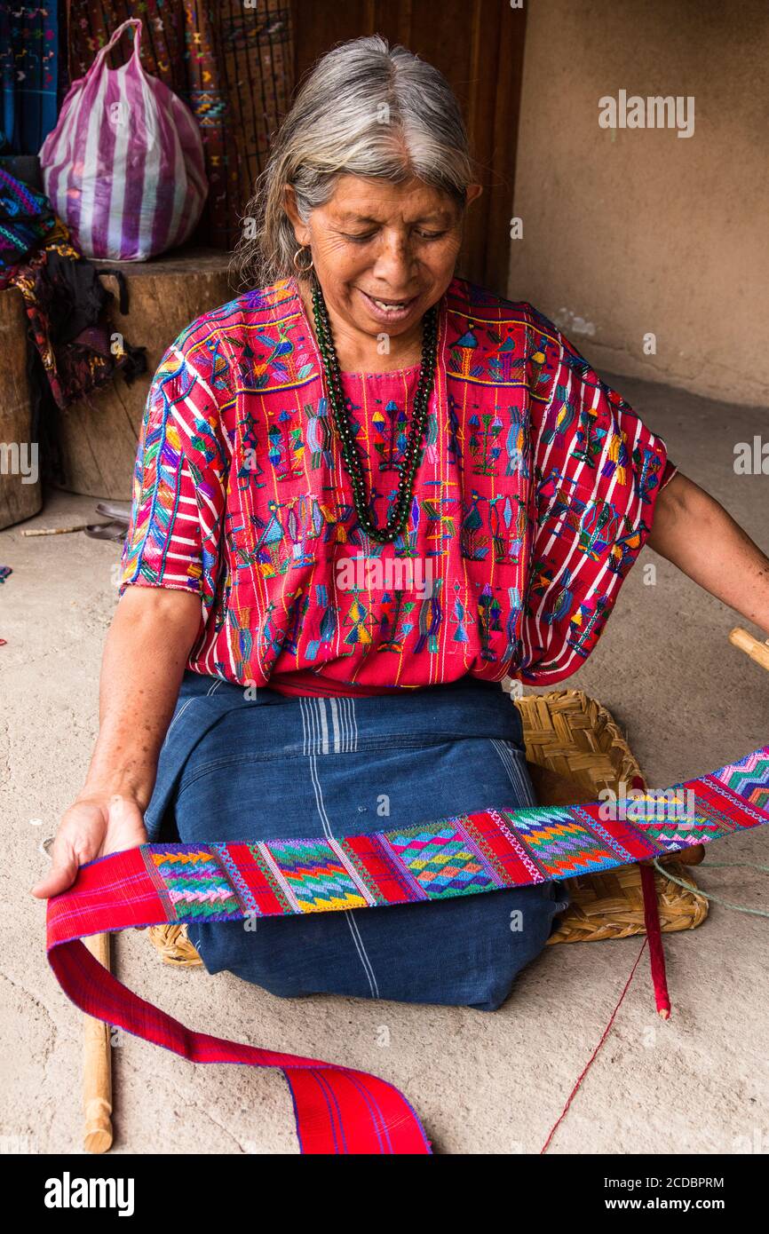 An older Cakchiquel Mayan woman in traditional dress examines the