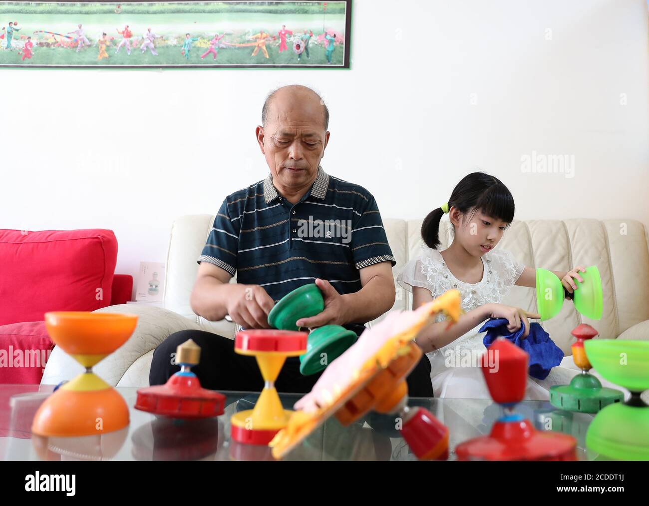 (200828) -- BEIJING, Aug. 28, 2020 (Xinhua) -- Dong Shulin (L) and his granddaughter Dong Yutong clean and fix diabolos at home in Beijing, capital of China, Aug. 11, 2020. Dong Shulin, 66, lives with his wife Mei Yongpei and his 9-year-old granddaughter Dong Yutong in Beijing. Dong Shulin started to play diabolo in 2003 and now the whole family are fond of playing this traditional folk game, in which one can throw and catch a spinning top by moving a cord fastened to two sticks. In Dong Shulin's home, over 70 diabolos were placed all around. Some of the diabolos were purchased and others were Stock Photo