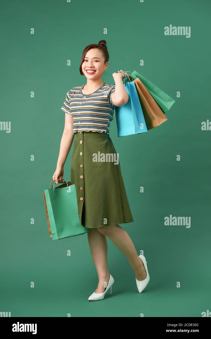 Full length portrait of a happy pretty girl holding shopping bags while ...