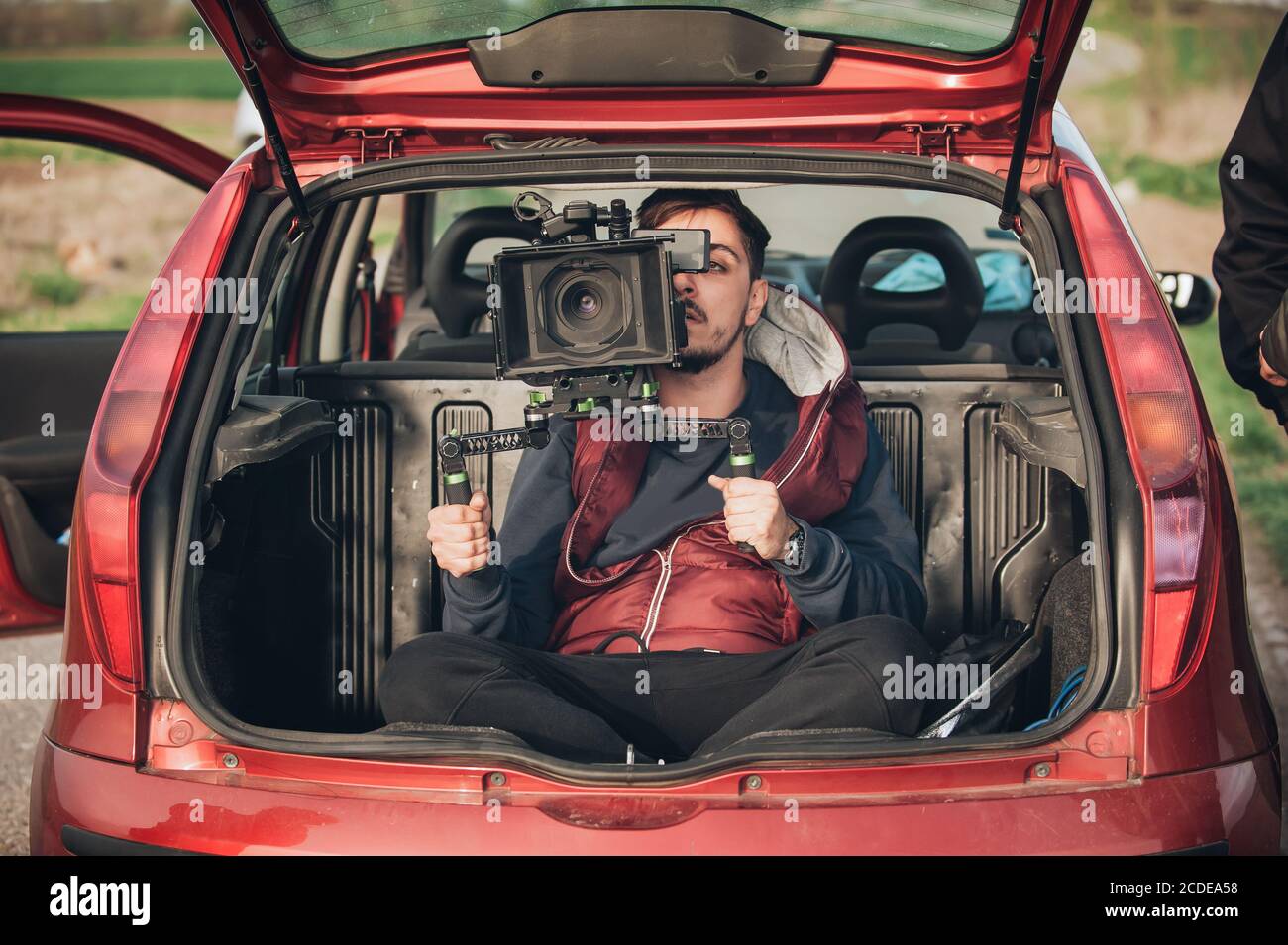 Behind scene improvisation. Cameraman from trunk of car shooting film scene on outdoor location