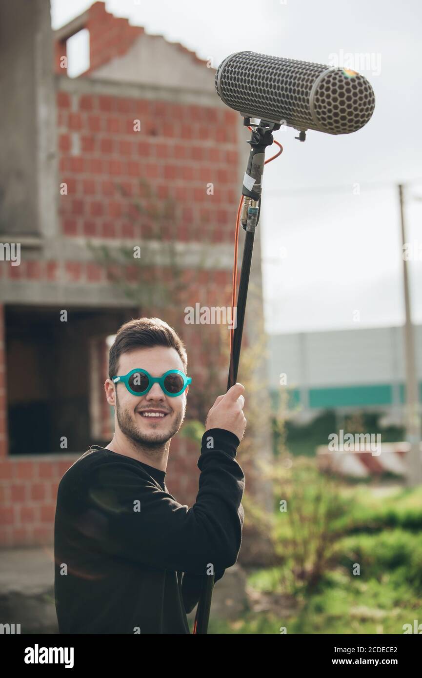 Behind the scene. Sound boom operator resting on the set and hold