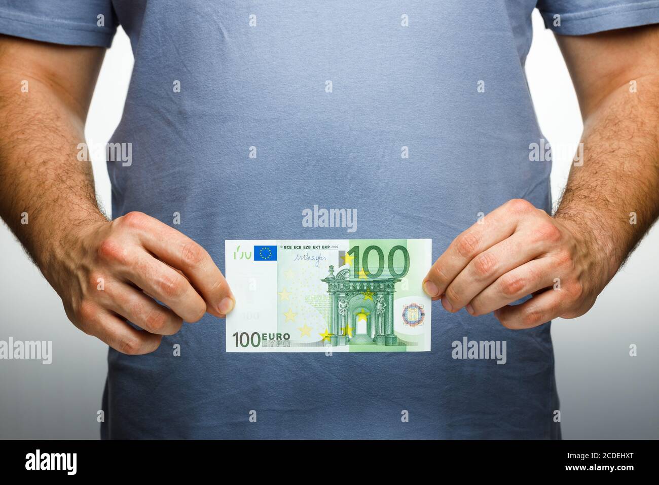 A man holds a one hundred euros in his hands. Financial and commercial concept. Stock Photo