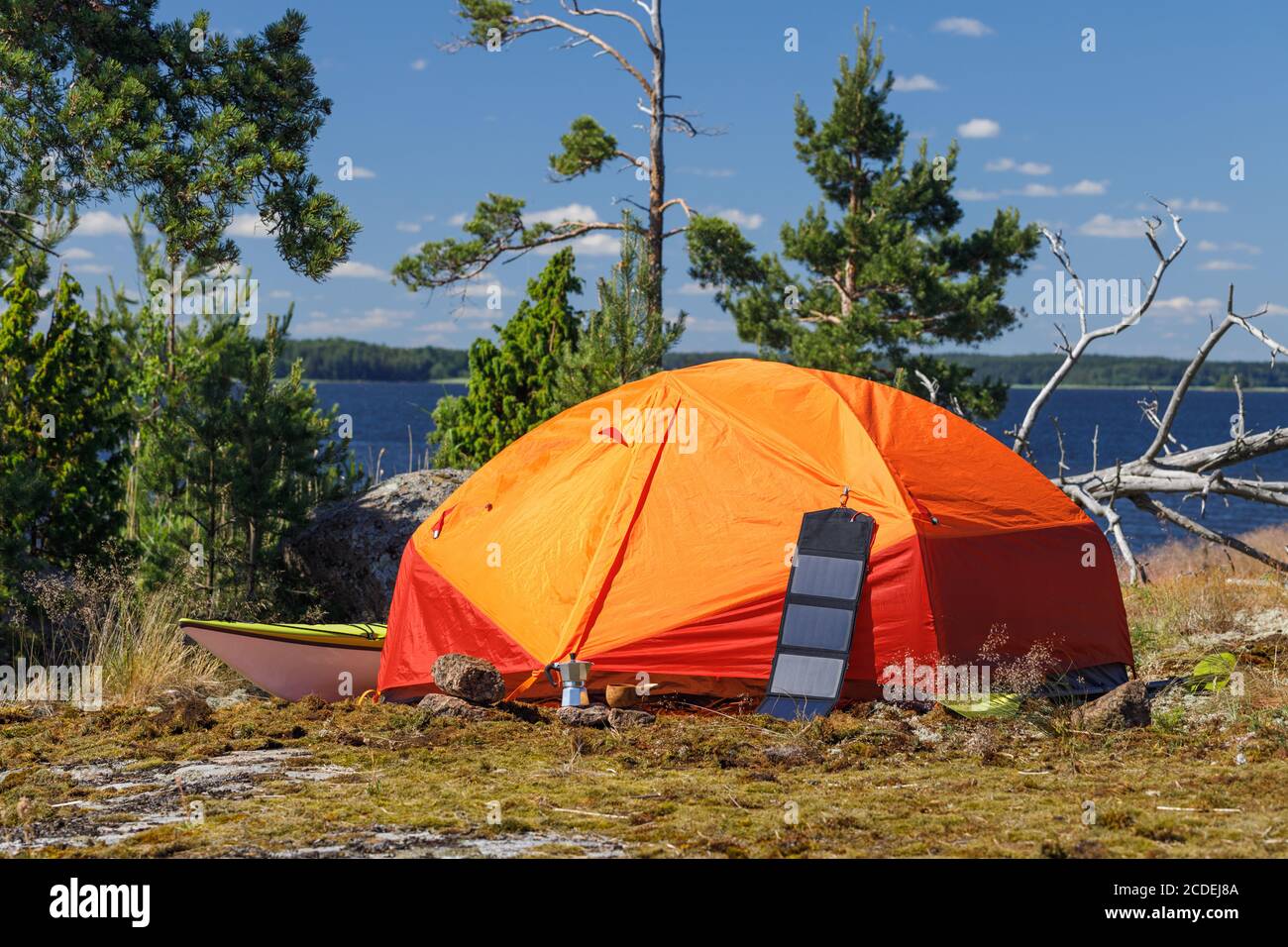 Orange tent tourist solar panel sea kayak coffee maker on the island. Camping equipment outdoor activities kayaking Stock Photo Alamy