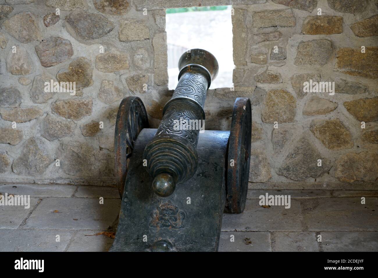 Old iron cannon leaned on the window in the fortress Stock Photo