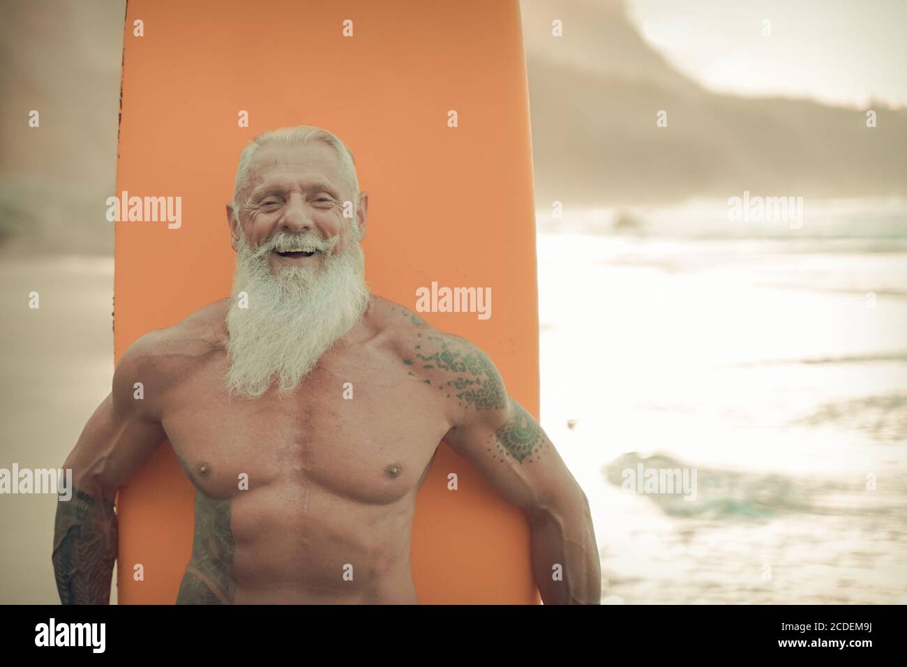 Senior man with orange longboard. Happy old guy having fun doing extreme sport. Joyful elderly concept - Image Stock Photo