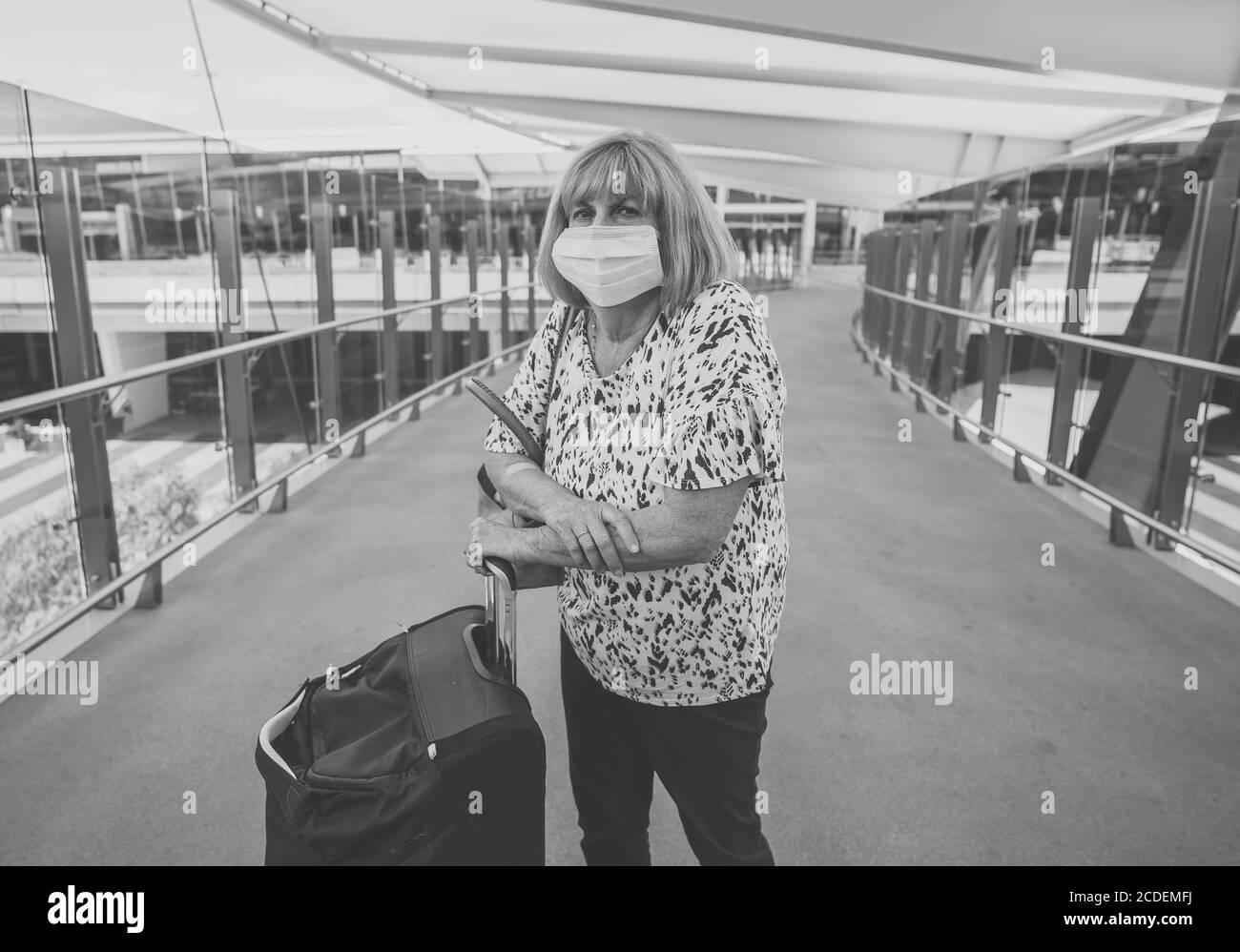 COVID-19 and travel in the New Norma. Senior woman with protective face mask at the airport terminal on her travel back to home country worried of qua Stock Photo