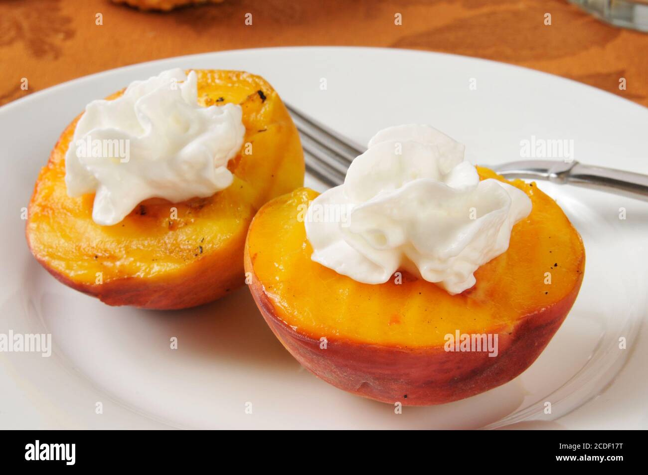 Lightly grilled peach halves with whipped cream Stock Photo Alamy