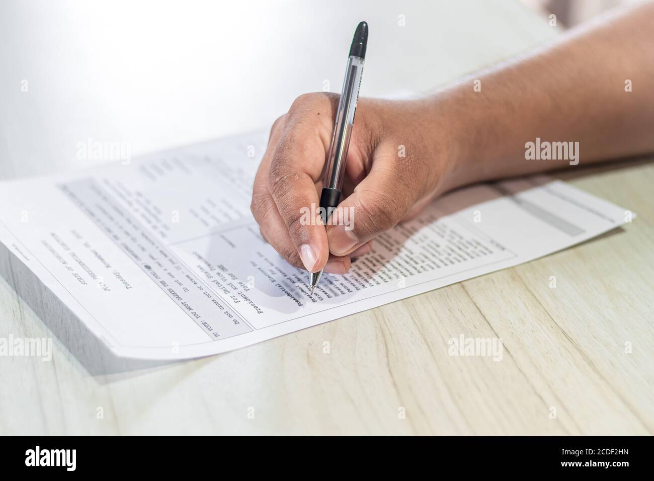 Voting Concept. Hand of an Asian man casts vote on the ballot paper in US Election. Stock Photo