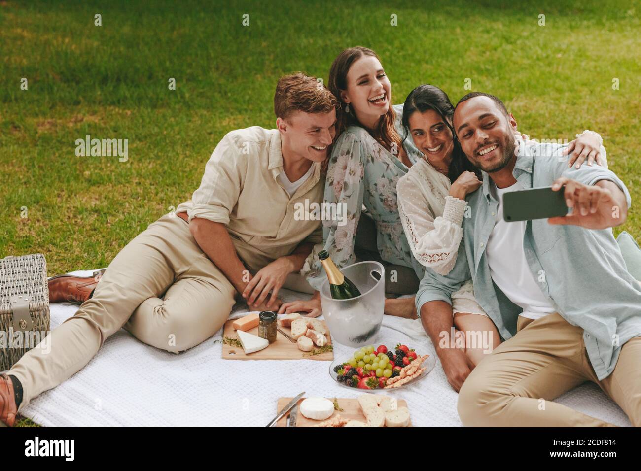 Group of happy friends having fun together and taking selfie using mobile phone. Young people on picnic taking self portrait of with smart phone. Stock Photo