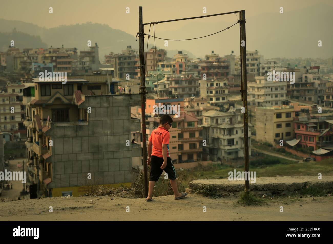 A child walking on roadside, through an alley gate leading to a residential area on the outskirts of Kathmandu, Nepal. Stock Photo