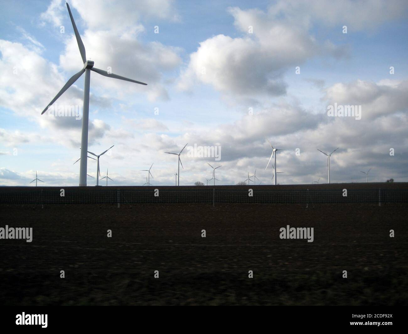 wind turbines farm on a field with cloudy sky Stock Photo - Alamy