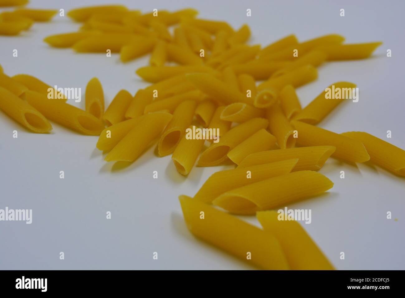 Italian yellow pasta, noodles pasta, durum wheat feathers scattered over white background Stock