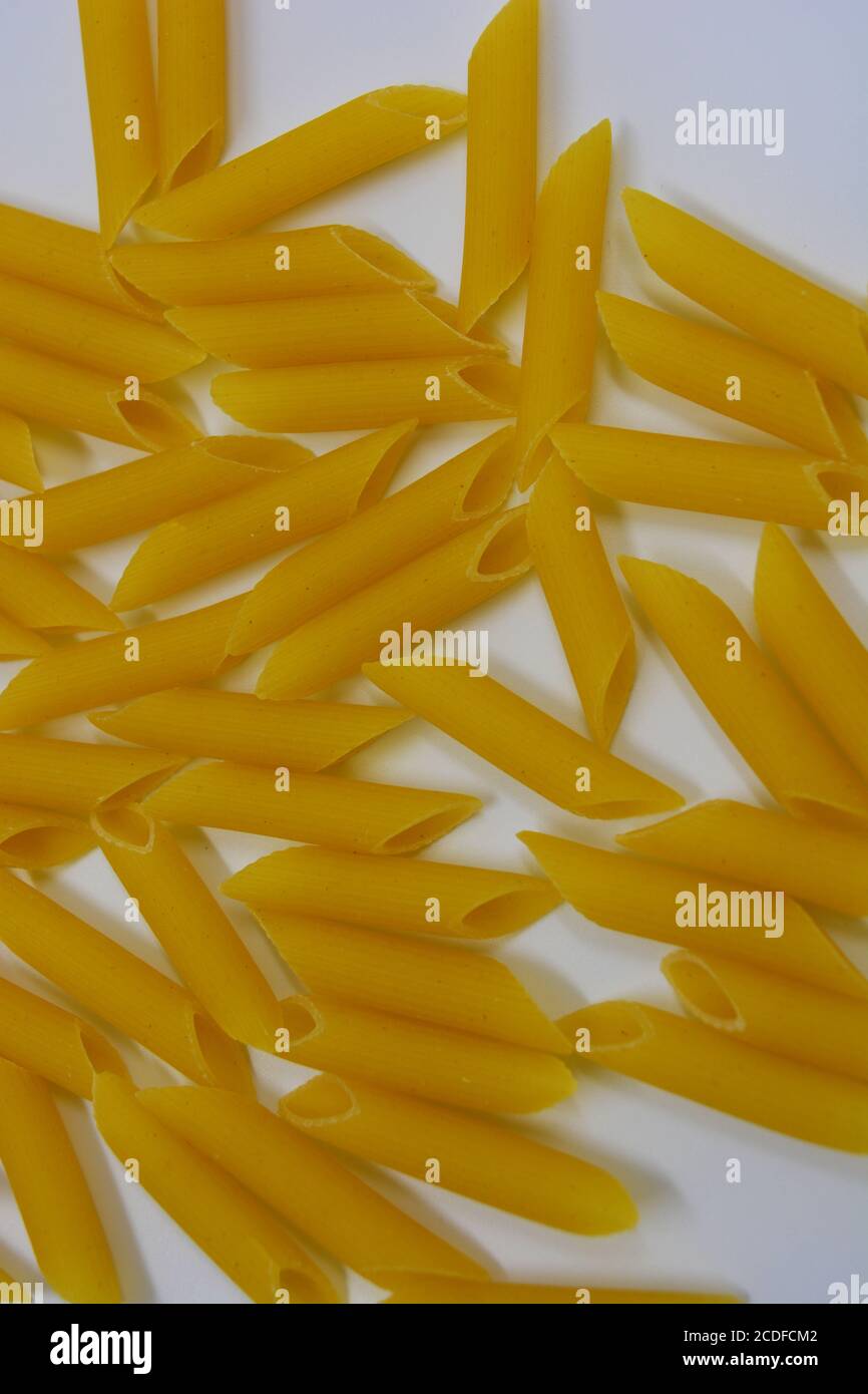 Italian yellow pasta, noodles pasta, durum wheat feathers scattered over white background Stock