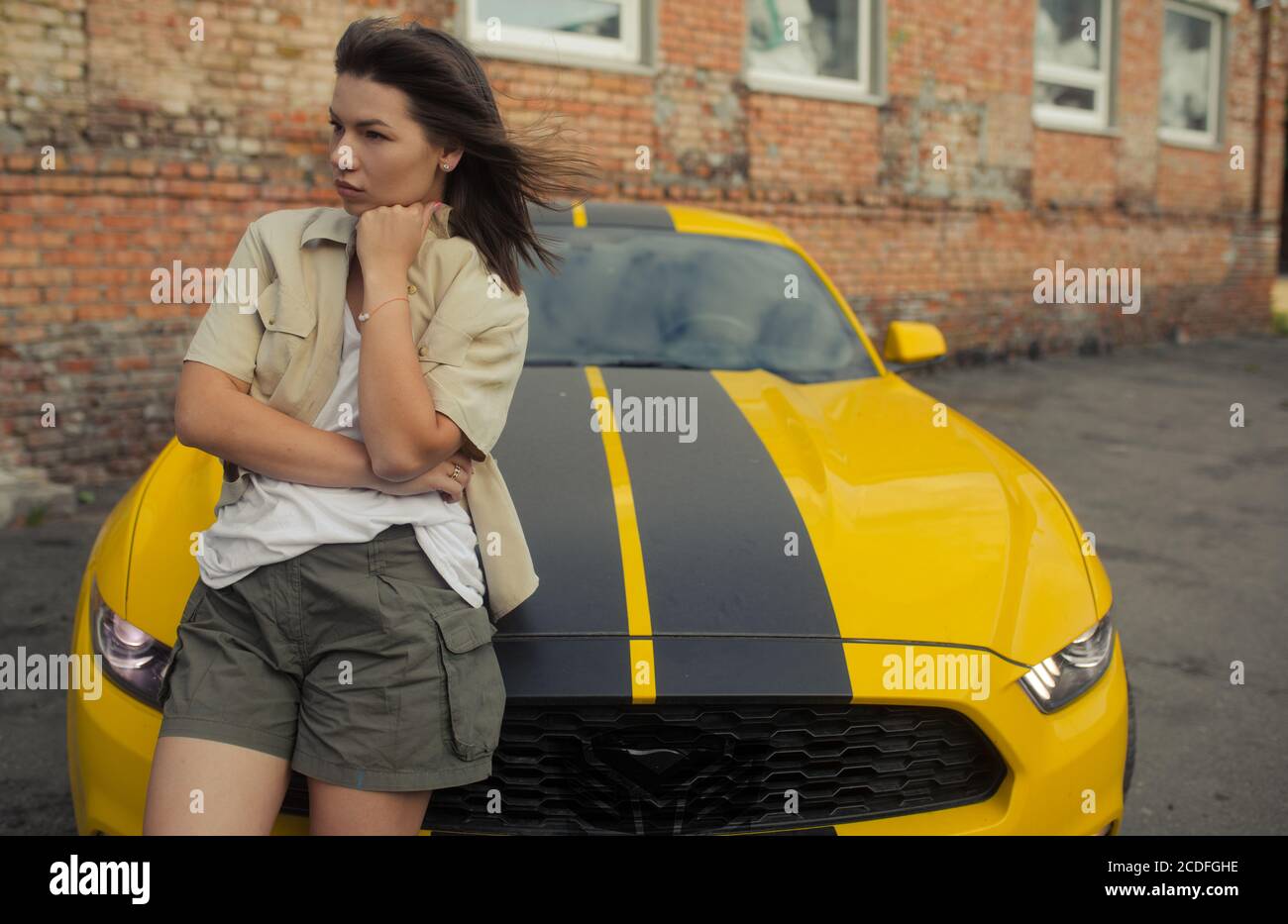 Girl stands near yellow car with the autobot logo or robot transformer. Stock Photo