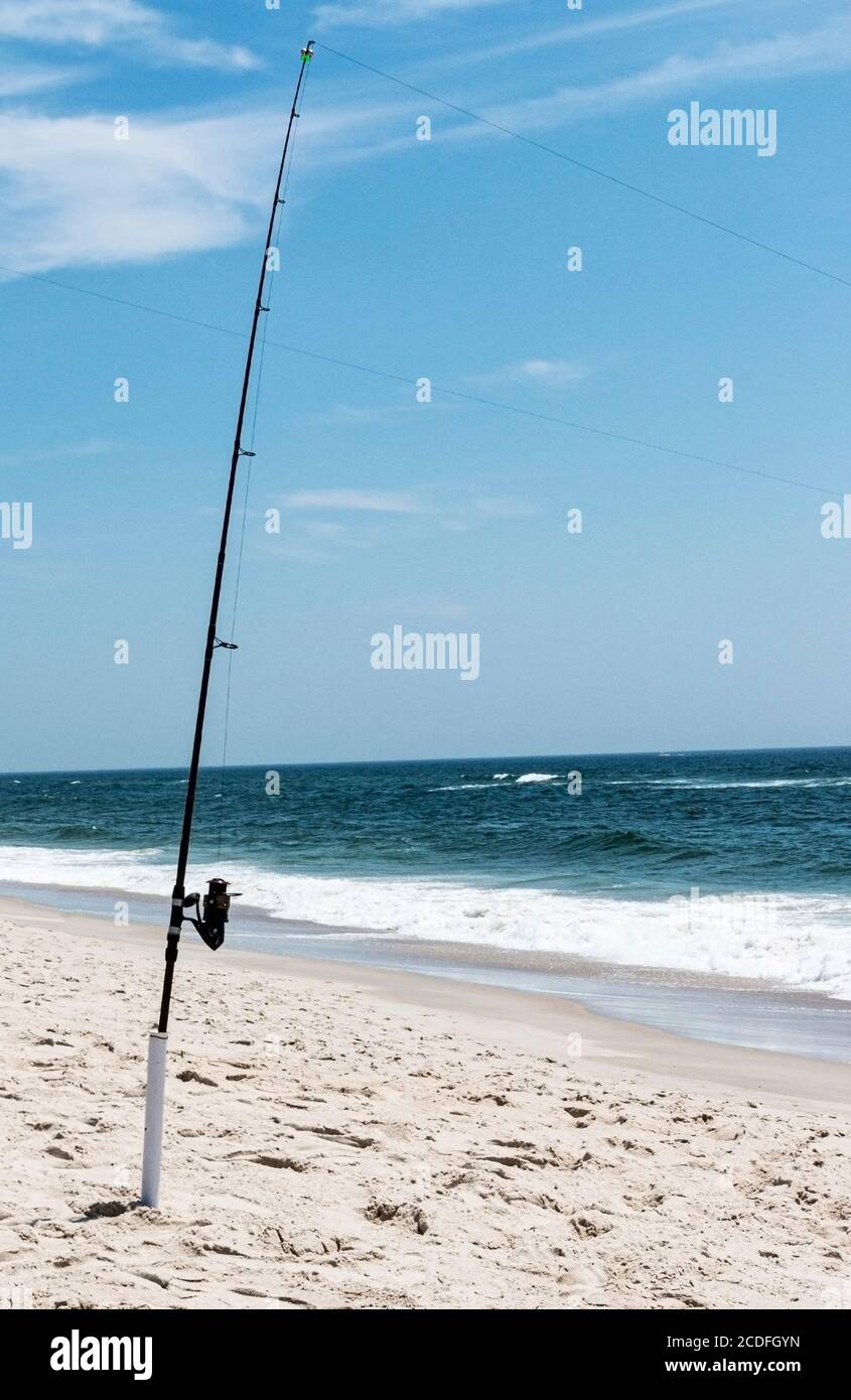 A fishing pole with its line cast in to the Atlantic Ocean standing upright  in a