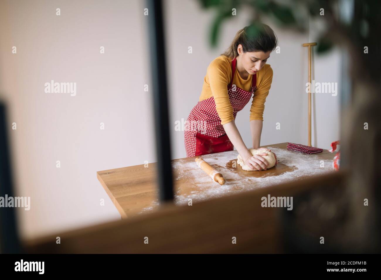 Young woman kneading dough with hands for baking homemade bread Stock