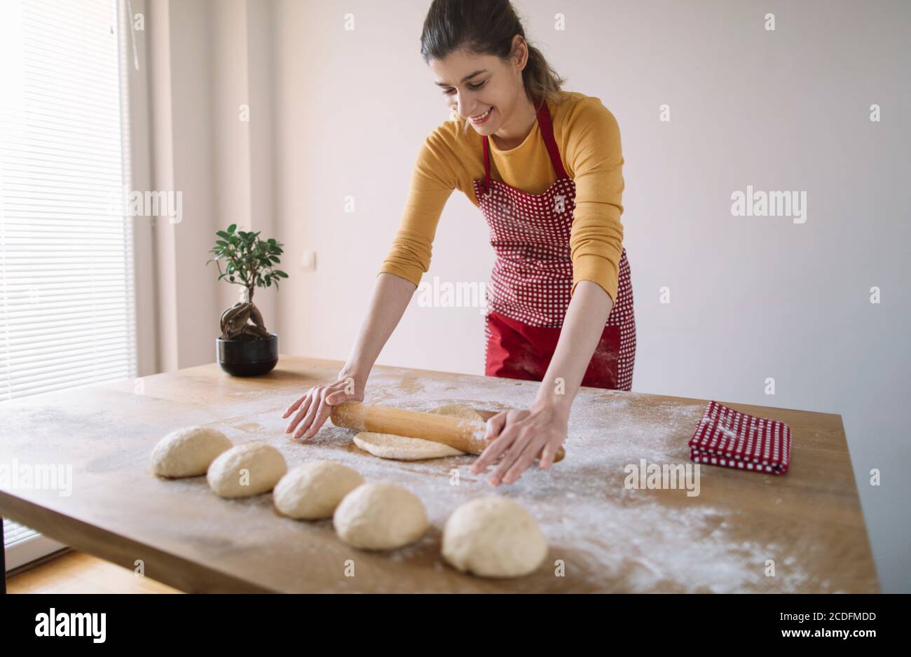 Young woman kneading bread dough with rolling pin Stock Photo Alamy