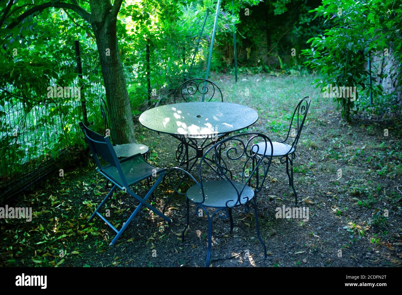 Table and chairs in a shady garden in southern France Stock Photo