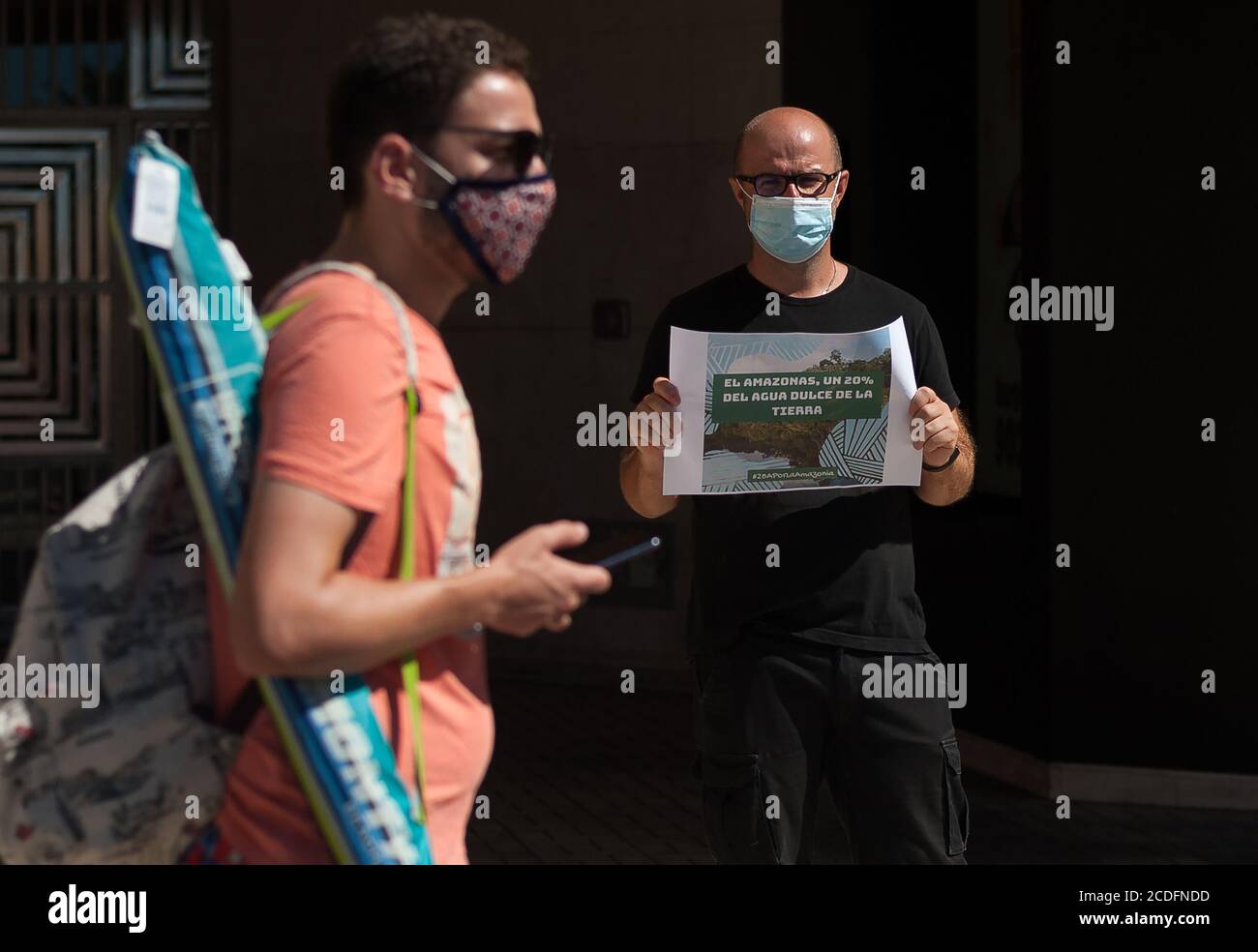 A protester wearing a face mask holds a placard expressing his opinion during the demonstration at La Malagueta square in Malaga.From 28 to 30 August members of 'Extinction Rebellion' movement have organized several actions to alert people about the situation of Amazonian Selva, considere the 'lungs of the world'; against commercial treaty between EU - MERCOSUR agreed for Brazilian president Jair Bolsonaro which would cause the deforestation of Amazonia and a negative impact in the climate while forest fires continue rising in the region. Stock Photo