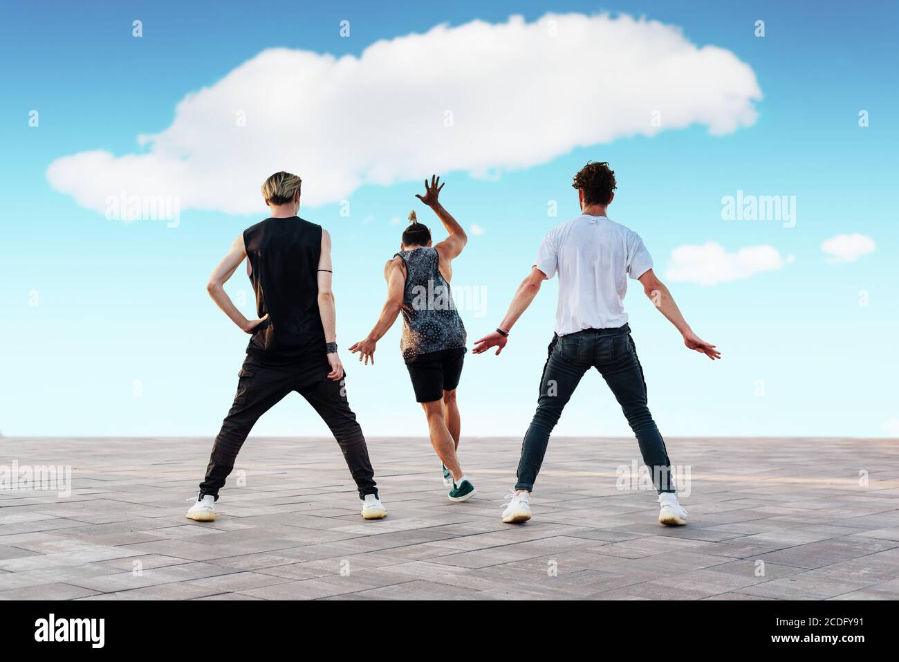 Three unrecognizable young men dancing sport dances, hip-hop or break-dance outdoors. Teenage lifestyle and urban youth culture concept. Street dance. Stock Photo