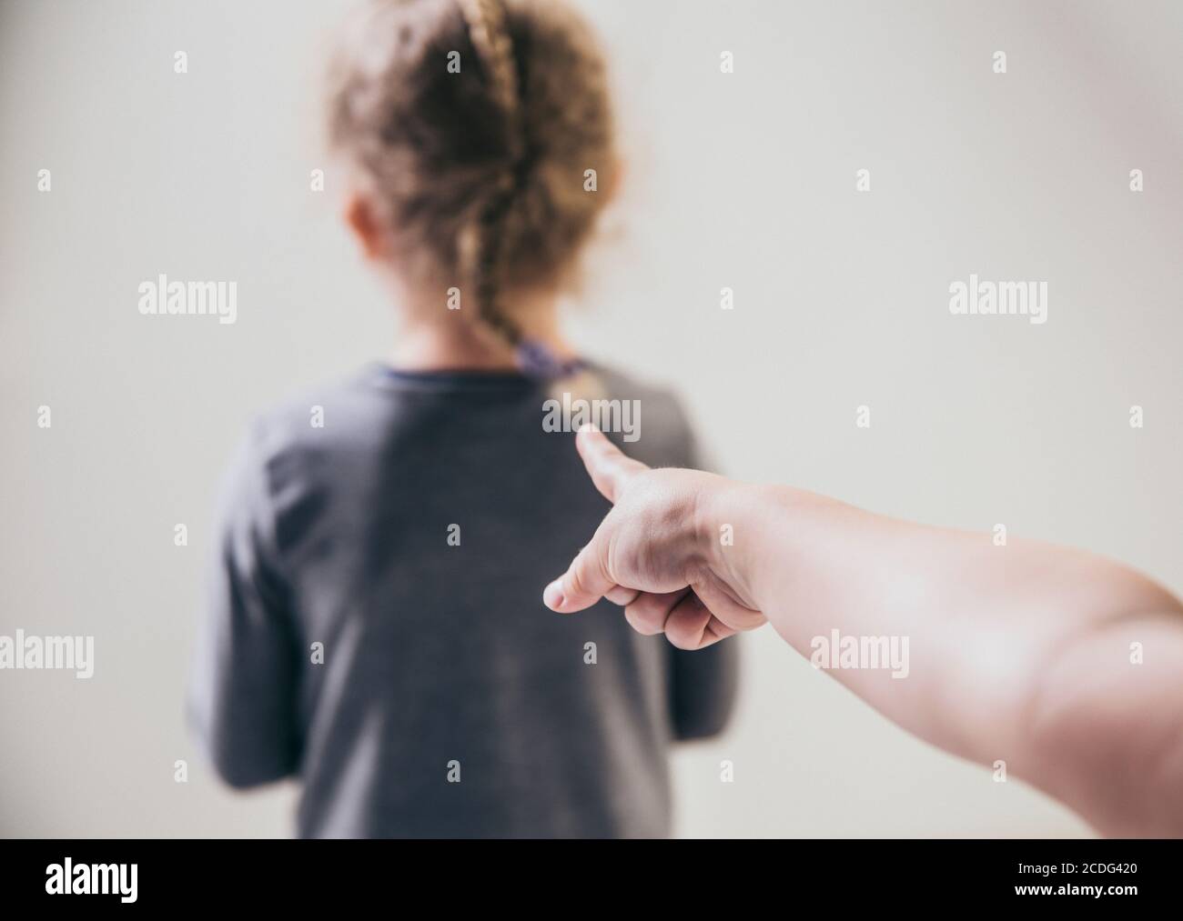 Child bully pointing finger at blurred unrecognizable victim and talking behind back. Bullying concept. Stock Photo