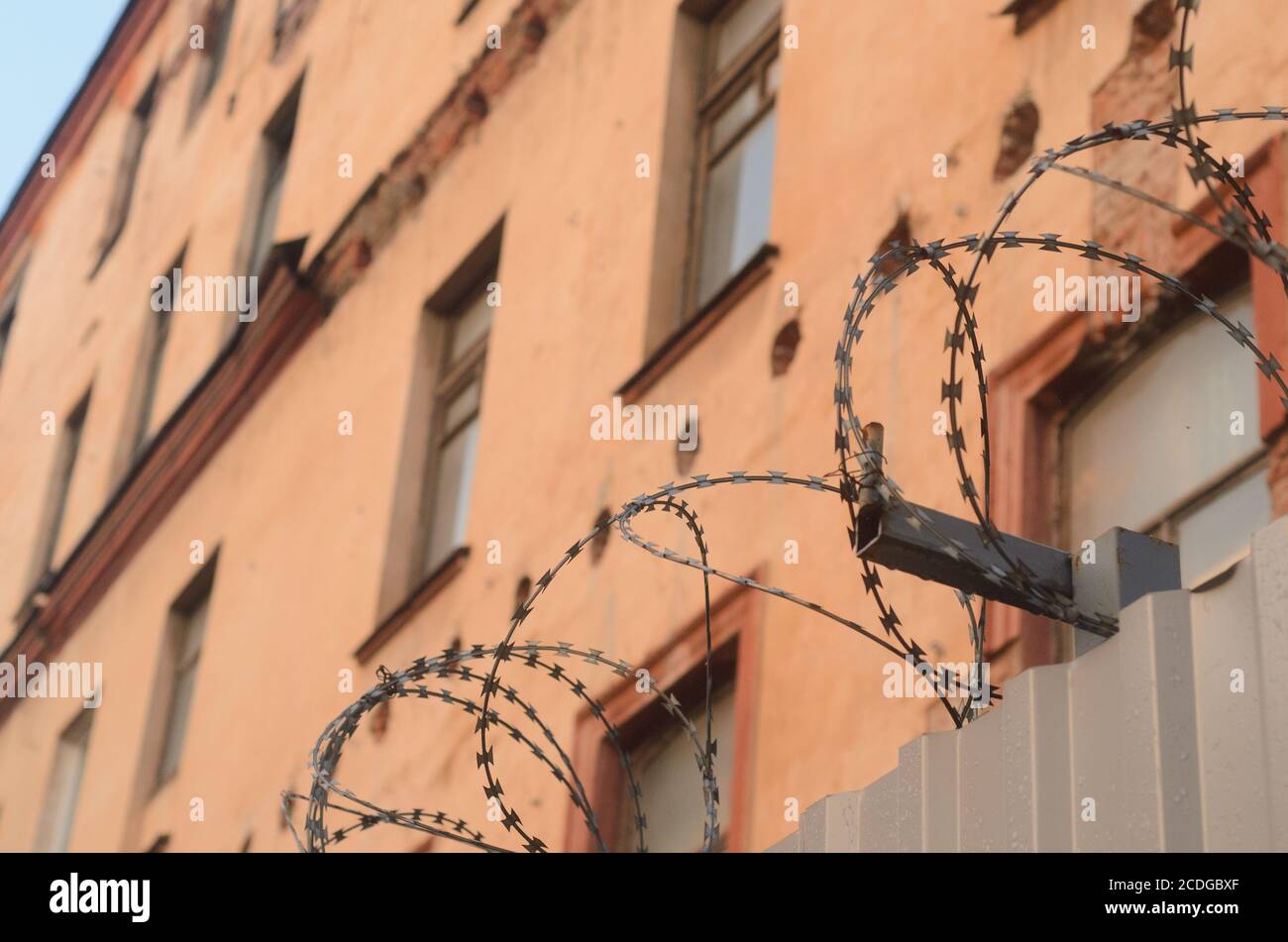 Barbed wire fence wall on security building background. Stock Photo