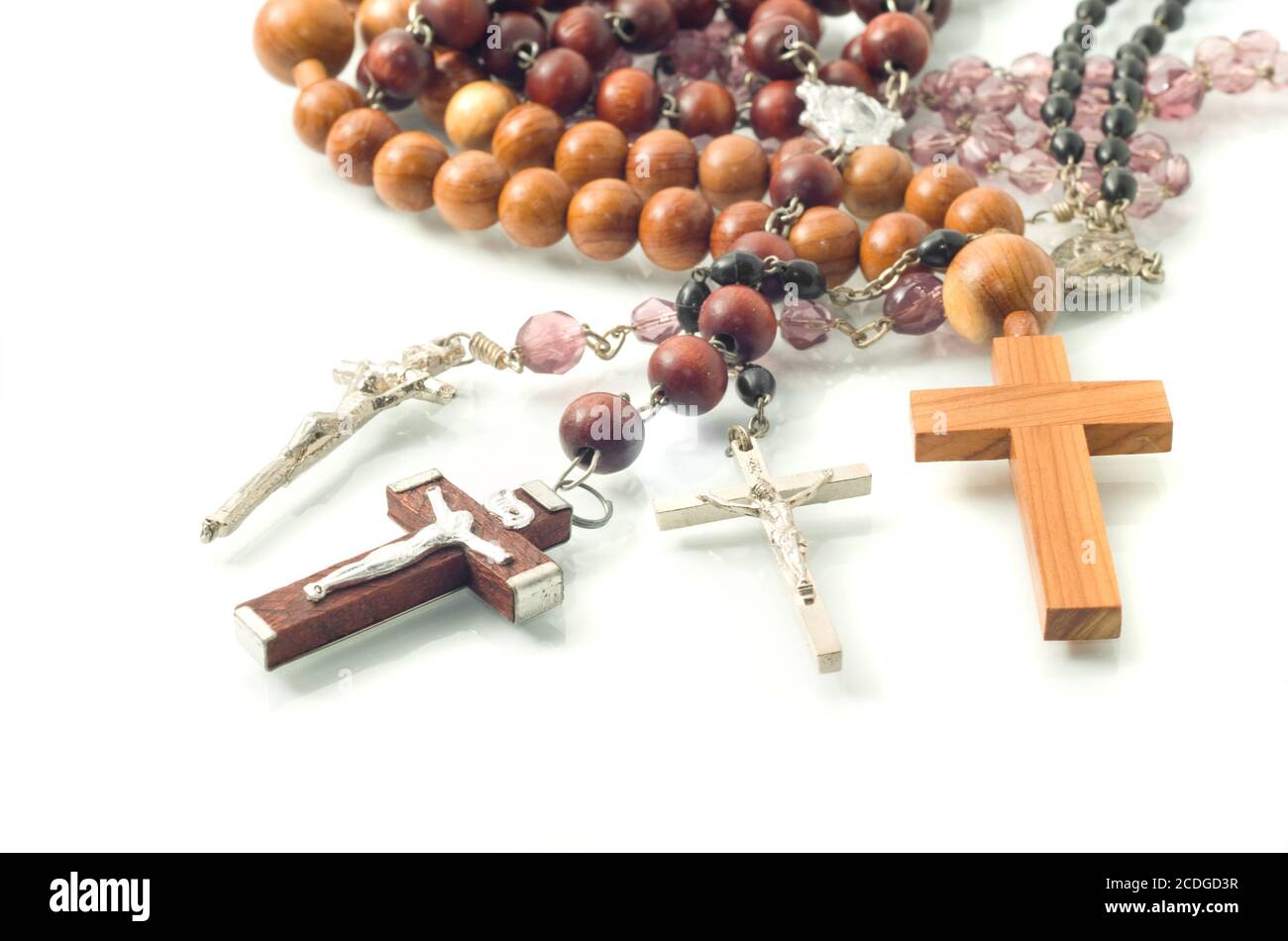 Rosary beads over white with focus on crosses Stock Photo