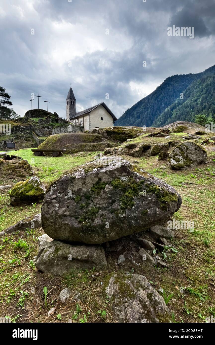 The medieval Santo Stefano church stands on a rocky spur at the entrance of the Genova Valley. Carisolo, Trentino, Italy. Stock Photo