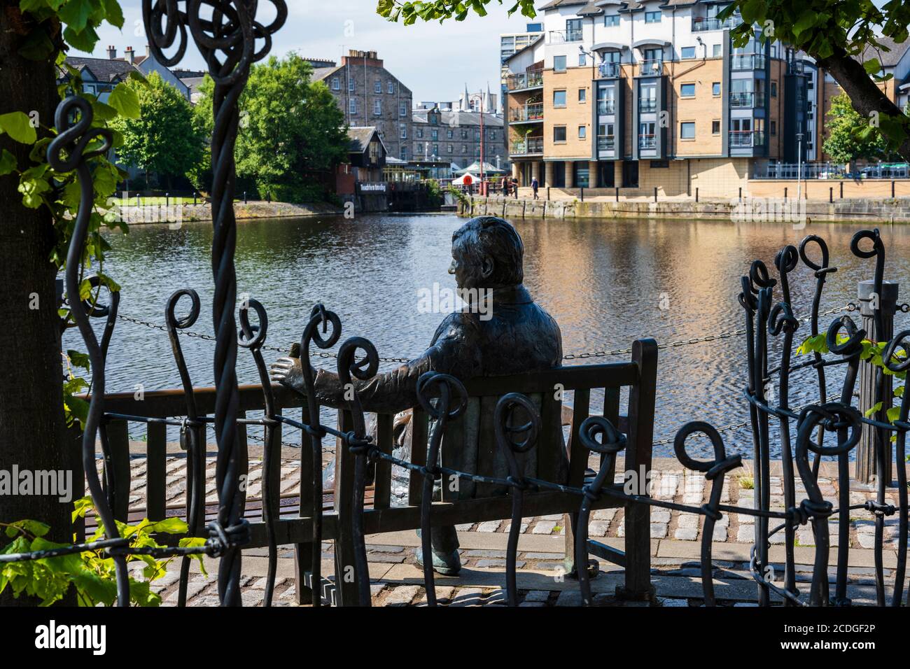 Life size bronze sculpture of Sandy Irvine Robertson OBE by Lucy Poett overlooking the Water of Leith on The Shore at Leith, Edinburgh, Scotland, UK Stock Photo