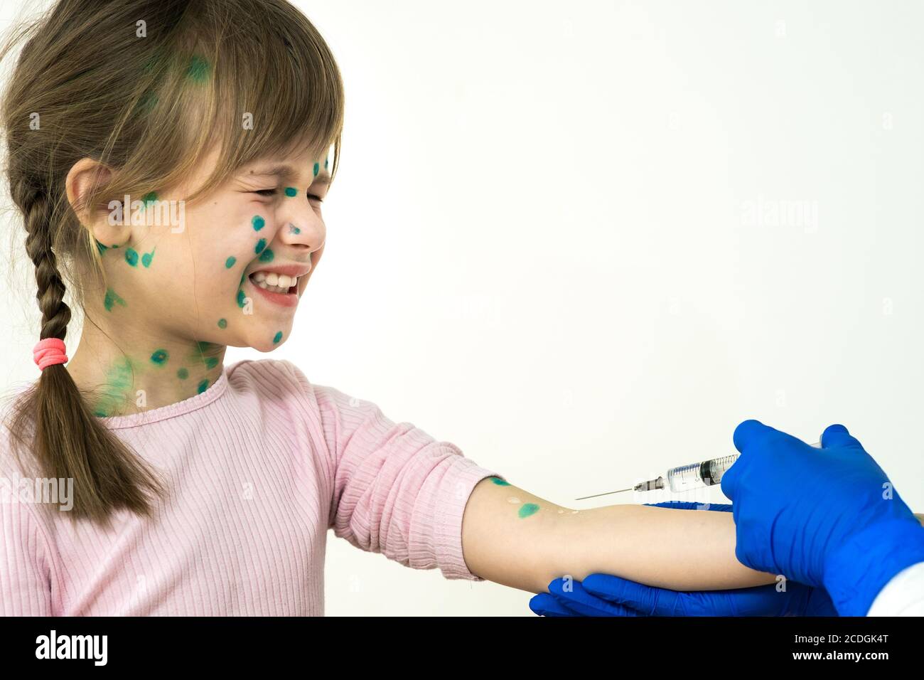 Doctor making vaccination injection to an afraid child girl sick with chickenpox, measles or rubella virus. Vaccination of children at school concept. Stock Photo