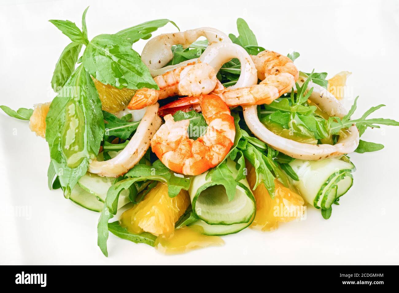 Organic seafood green salad with shrimps, squid rings, cucumber and arugula decorated with basil leaves Stock Photo