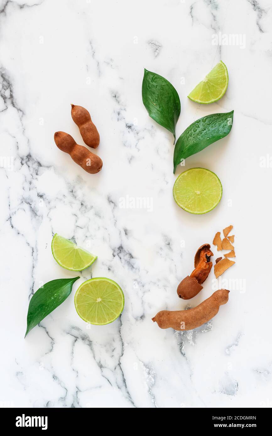Flat lay mock up with sweet tamarind and green lemon on a marble background suitable for cosmetics advertising Stock Photo