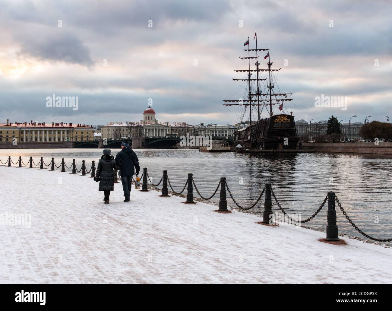 A couple walking along Neva River in winter, with the Vasilyevsky Ostrov in the background, Saint Petersburg, Russia Stock Photo