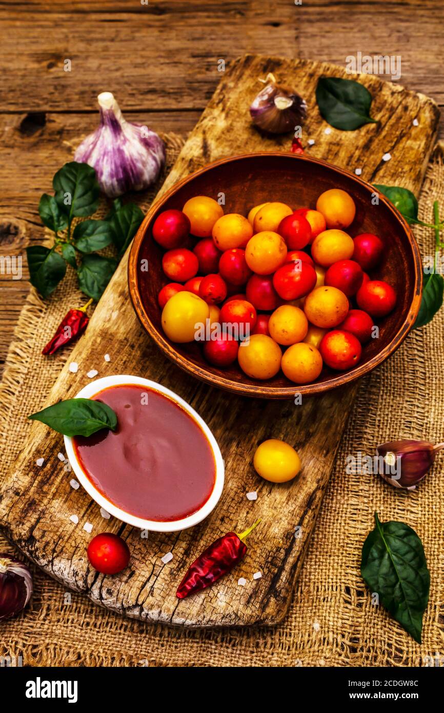 Tkemali Georgian cherry plum sauce with garlic and hot pepper. Traditional dip from ripe fruits and spices. Vintage wooden background, close up Stock Photo