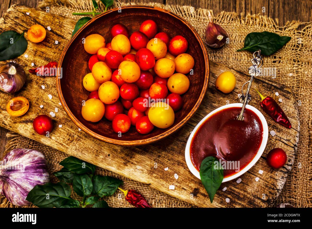 Tkemali Georgian cherry plum sauce with garlic and hot pepper. Traditional dip from ripe fruits and spices. Vintage wooden background, top view Stock Photo