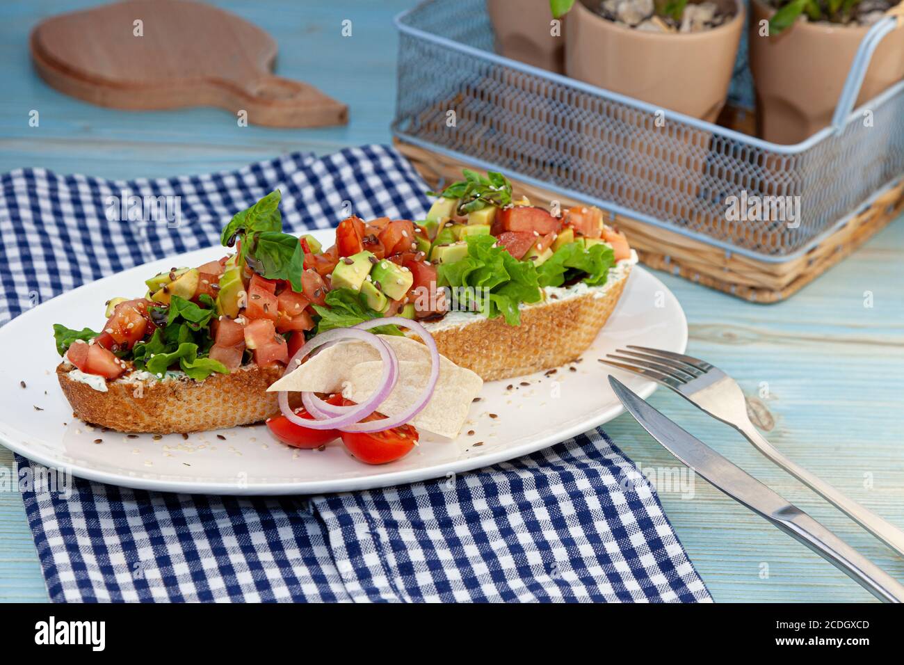 A large sandwich with avocado, tomato, basil and cheese spread. Toast on white baguette bread. Close-up still life on the table. Sandwich food snack Stock Photo
