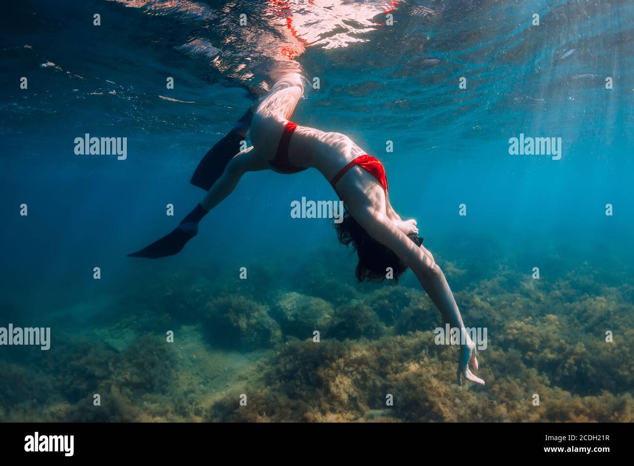 Slim Woman Freediver Posing Underwater In Blue Sea With Sun Rays