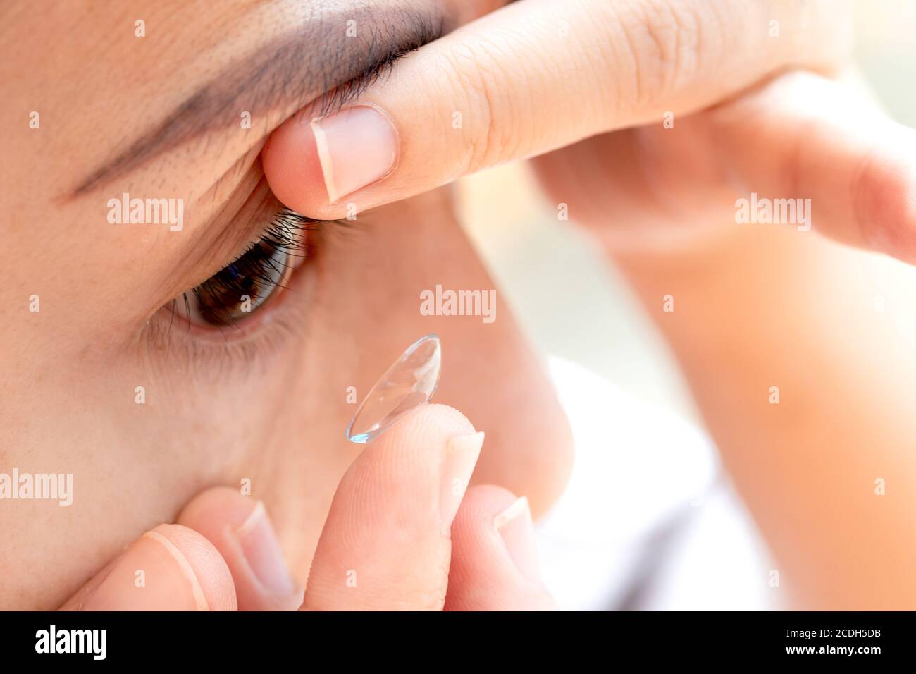 Close up young woman wearing contact lens. asian woman putting eye lenses with hands Stock Photo