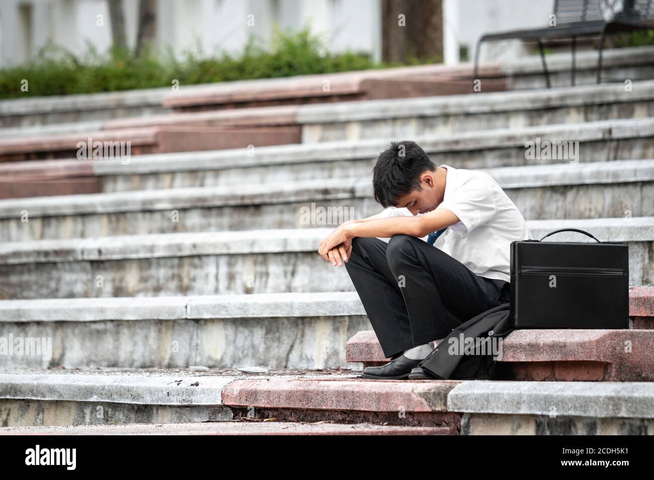 Failure unemployed stressed young asian business man. A young businessman sitting desperate on the stairs because low economic crisis. layoff. Stock Photo