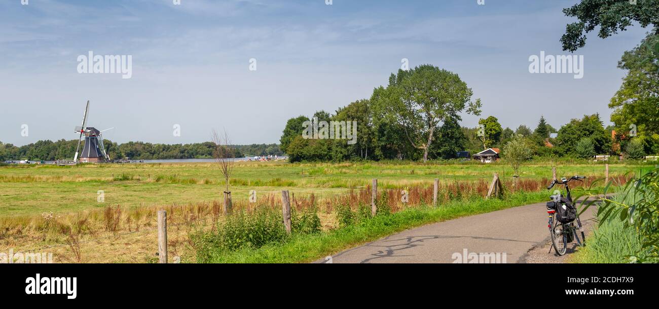 Panoramic view of windmill De Helper and bike along Patersolwdsemeer near Groningen in the Netherlands, Europe Stock Photo