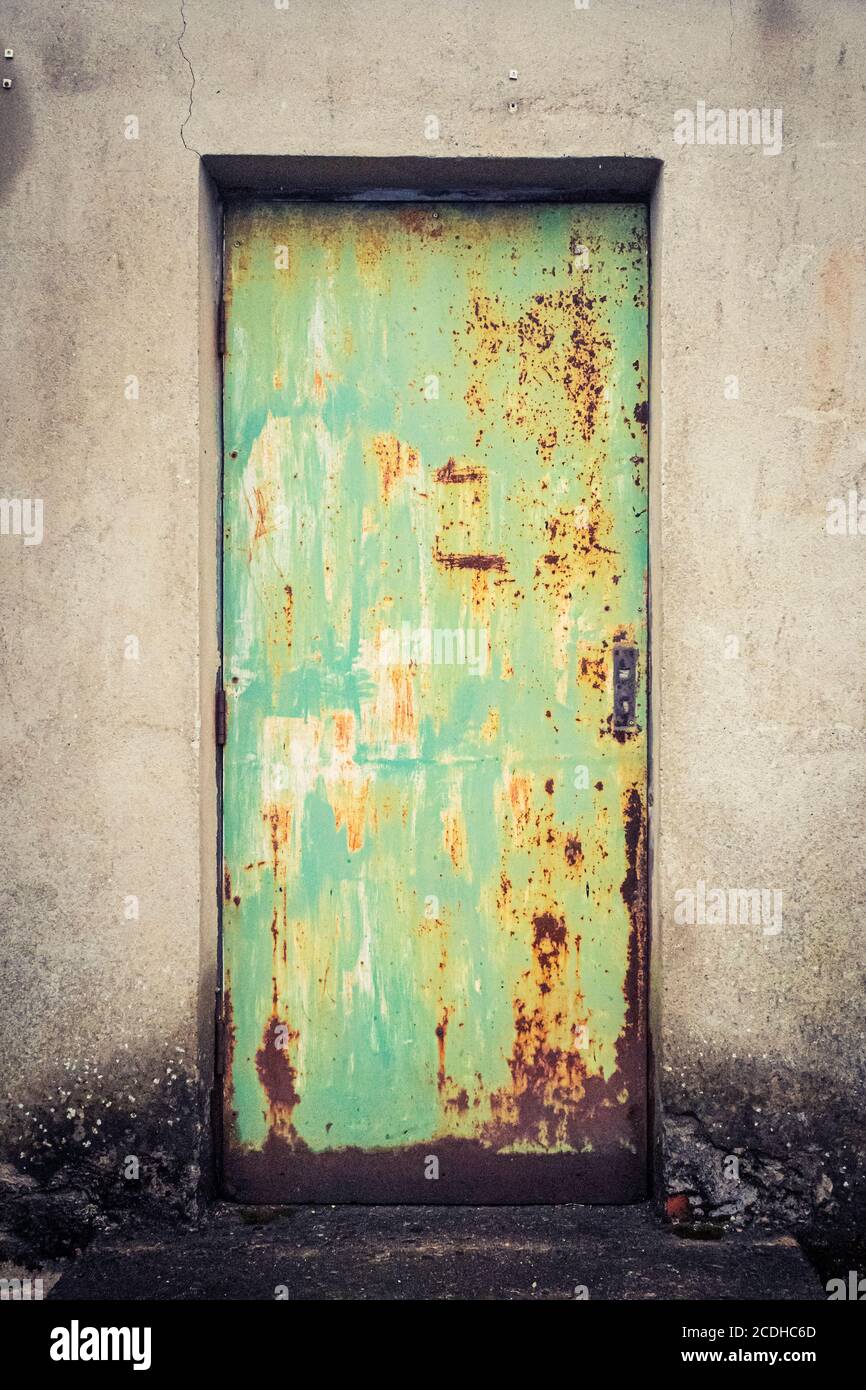 A rusty green painted metal door in the outside wall of a building in Consett, County Durham, UK Stock Photo