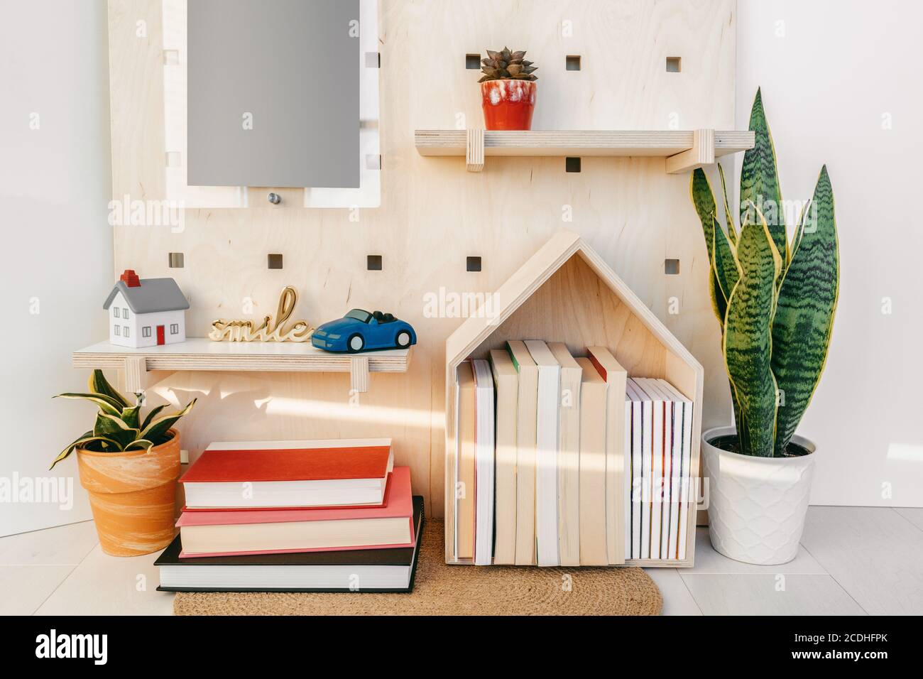 Home decor cozy wall shelves with books and toy car. New house decoration concept. Plants, wooden shelf, happy sign Stock Photo